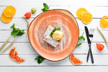 Strudel with apples and ice cream on a plate. Dessert. On a wooden background. Free copy space. Top view.