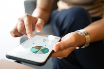 Asian woman looking at some charts on her mobile phone while sitting at coffee shop