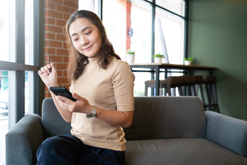 Asian woman using her mobile phone in cafe.