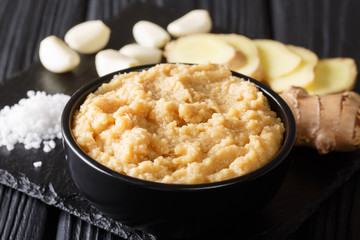 Raw spicy ginger garlic paste for asian cuisine close-up in a bowl on a black table. horizontal