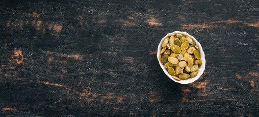 Pumpkin seeds. On a black wooden background. Top view. Free copy space.