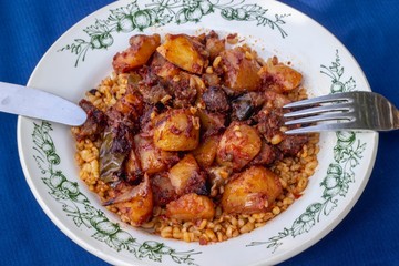 Clean shoot of traditional turkish meal with meat and potato on the blue table with fork and knife