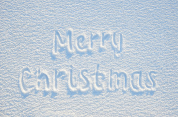 Merry christmas text written on snow for texture or background - winter holiday concept. Sunny day, bright light with shadows, flat lay, top view, clean and nobody