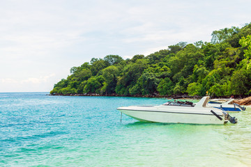 Naklejka na ściany i meble White motor boat docking on the beach with nature background.