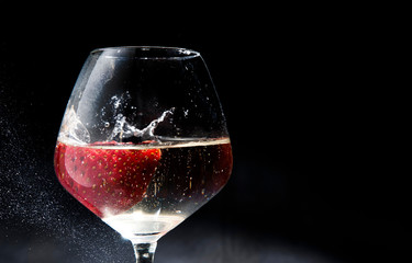 Strawberries put in white wine glass over black background