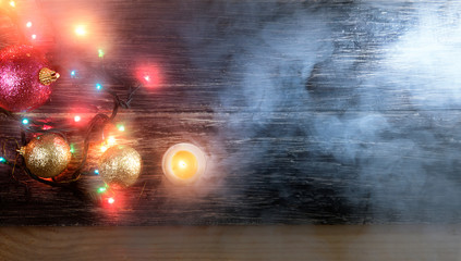 Christmas balls with candle and multi colored lamps on wooden floor