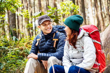 Smiling asian couple hikers with backpack looking at each other