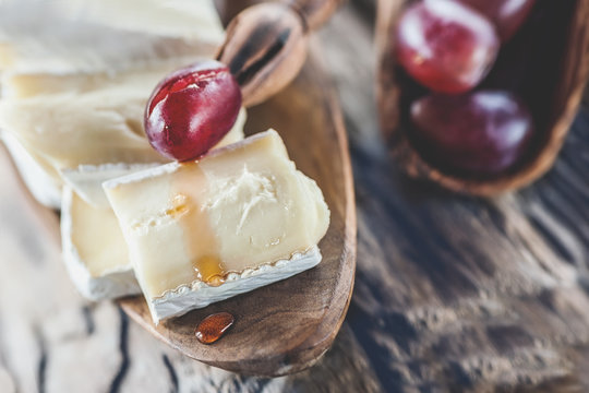 Organic homemade white brie cheese with pink grapes on a wooden Board