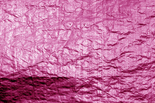 Crumpled transparent plastic  surface in pink color.
