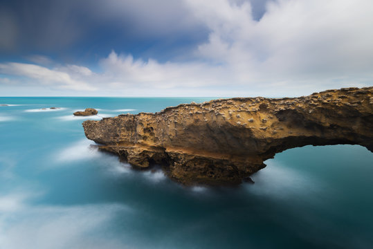 Vue sur un rocher pointu et son arche en pose longue