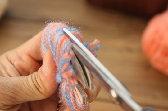 Hand Held Cotton Yarn With A Scissors Cut The Thread To Make Pompom