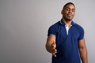 Young handsome African man wearing blue polo shirt against gray 