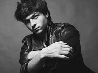 Portrait of Handsome Young Man. A Men in a Leather Jacket posing on a Gray Background. Black And White Photo