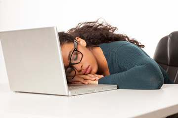 Young african tired woman slipping at her desk in front of laptop on white background