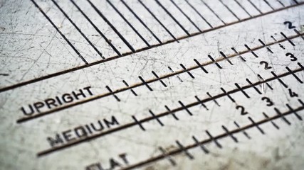 Camera slides from top to bottom to reveal close up footage of golf equipment measuring device showing words, numbers and black increment marks/lines.