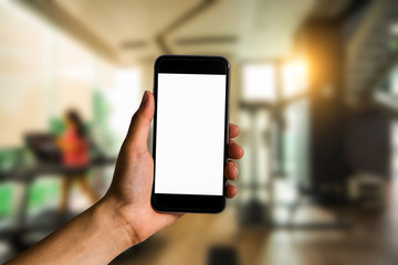 Hand holding white mobile phone with blank white screen  in gym.