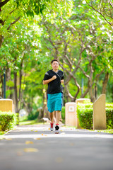 Obraz premium Young man in sports clothing jogging in park with headphone