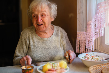 Elderly woman eat sitting at dinner table at home.