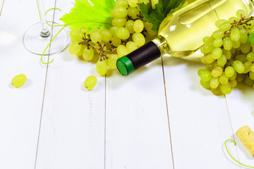 wine with branches of white grapes. On a wooden table.
