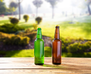 beer bottles on wooden table on park blurred background, alcoholic drinks celebration