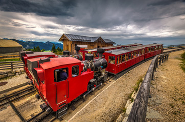 Alpine rack railway track to Schafberg, where steam train takes tourists on a mountain peak in the Austrian Alps near Salzburg. Two trains with steam locomotive waiting in Schafbergalpe station.