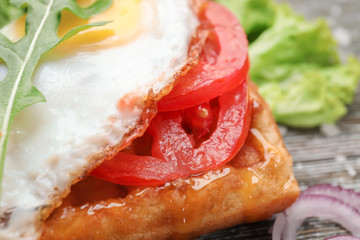 Delicious waffle with fried egg on table, closeup