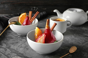 Bowls with sweet pears stewed in red wine on table
