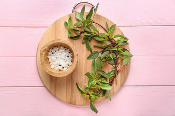 Wooden board with fresh aromatic basil and spices on color table