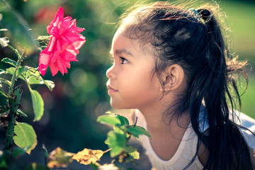 Young Girl Admiring a Pink Rose