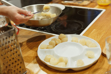 Hand of woman take cooking fry scallops in a pan with butter close up
