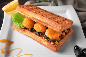Delicious waffles with chicken nuggets on plate, closeup