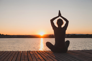 meditation and yoga practice at sunset, silhouette of woman, calmness and harmony