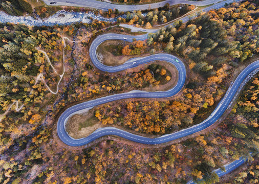 Travel by winding road in autumn forest, aerial landscape of fall season nature.