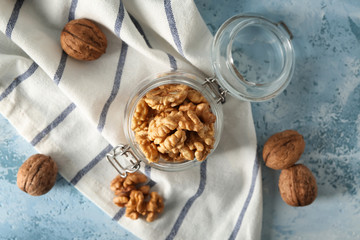 Glass jar with shelled walnuts on table