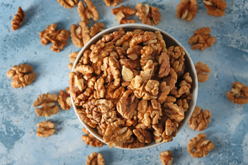Bowl with tasty walnuts on color table