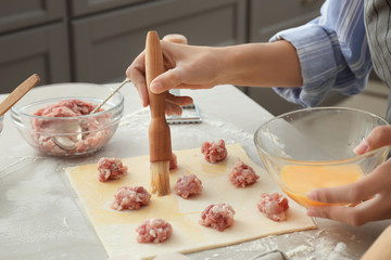 Woman making tasty ravioli on table