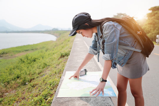 Young asian traveler searching direction on location map while traveling during holiday vacation.