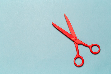 Red scissors on light blue background close up