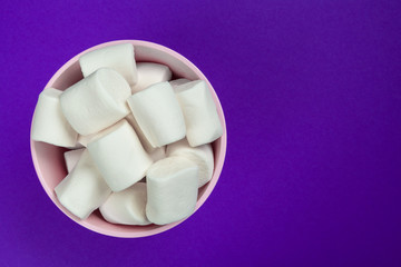 marshmallow laid out on violet paper background.