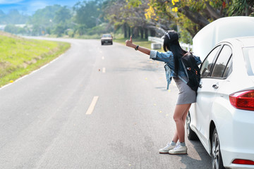 Young asian traveler with backpack and map hitchhiking on the road while traveling during holiday vacation