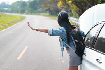 Young asian traveler with backpack and map hitchhiking on the road while traveling during holiday vacation