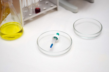 .laboratory equipment, test tubes with colored liquids, Petri dish of microorganisms on white background