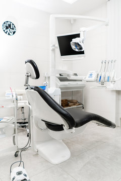Vertical view of a dentist room with black seat. Modern dental practice. Dental chair and other accessories used by dentists