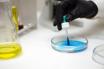  laboratory worker in a white coat working with chemicals under a microscope