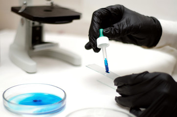 laboratory worker in a white coat working with chemicals under a microscope
