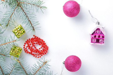 Christmas decorations. Spruce branches and holiday decorations on white background. Pink balls and toy house. Red necklace and golden boxes for festive Christmas tree