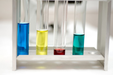 .laboratory equipment, test tubes with colored liquids, Petri dish of microorganisms on white...