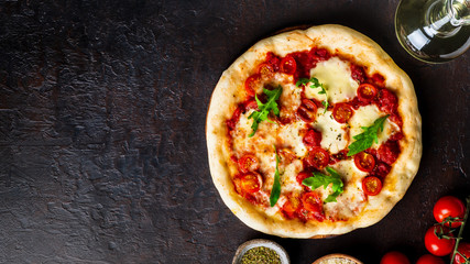 hot homemade Italian pizza margherita with mozzarella and tomatoes on dark brown stone table, top view, copy space