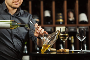 Close up portrait of caucasian sommelier pouring white wine in decanter
