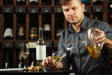 Sommelier pours white wine from decanter to the glass